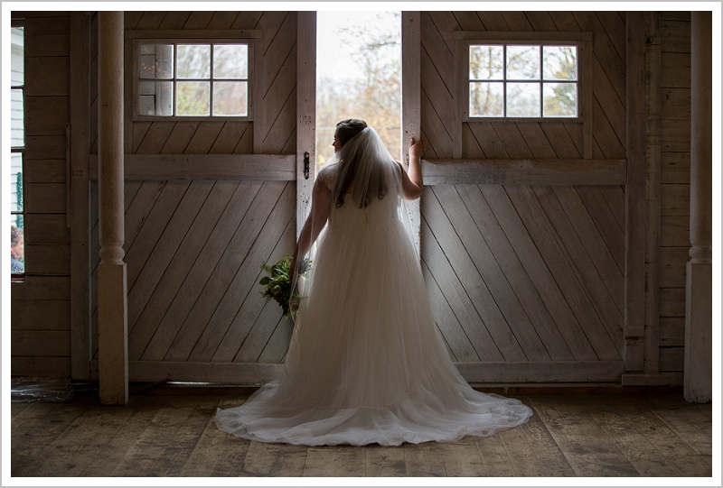 Bride looking through barn doors - Jason and Angela's Hardy Farm Wedding in Fryeburg Maine