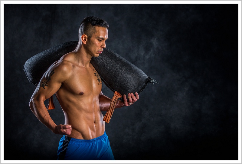 OCR Athlete Kiaran flexing with weight bag on shoulder