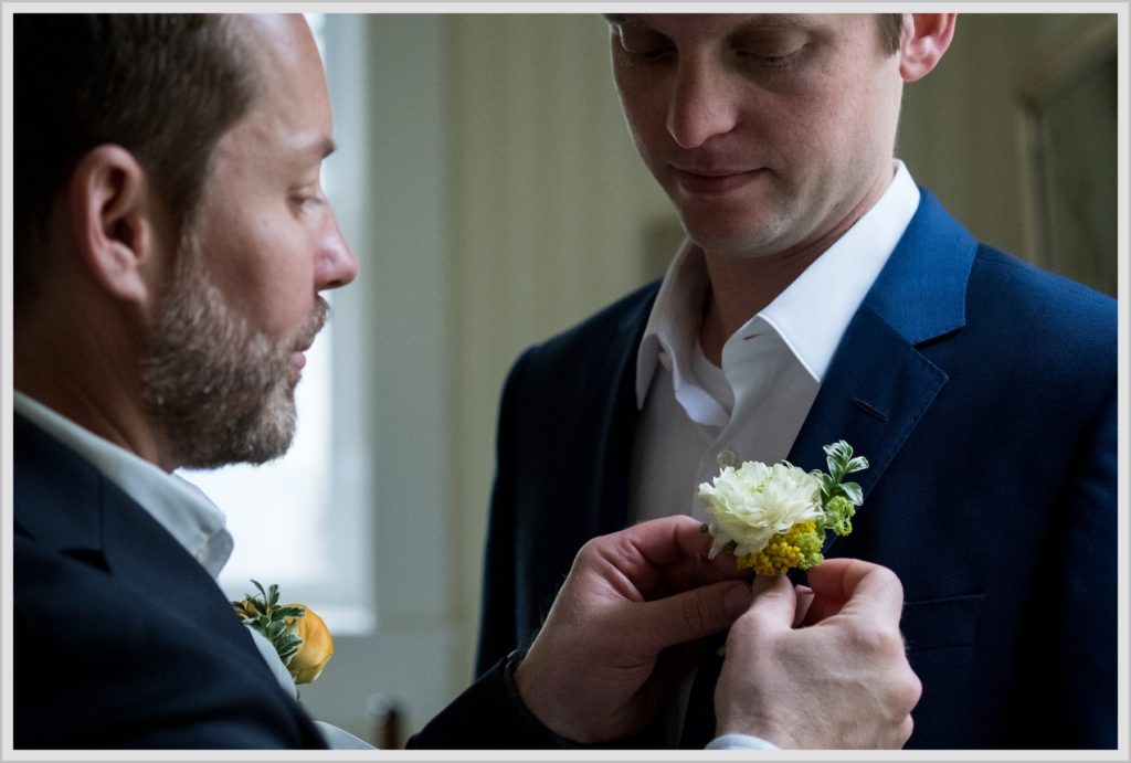 Katie and James' Hidden Pond Wedding | Putting the boutonniere on the Groom