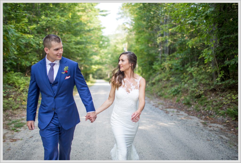 Dan and Amanda's Stone Mountain Arts Center Wedding Featured in Real Maine Weddings | bride and groom walking down dirt road hand in hand