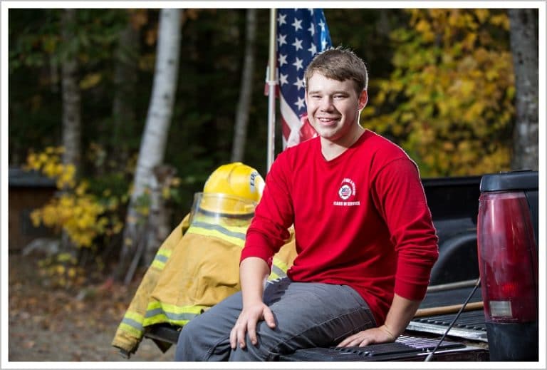 Joseph, Senior at Camden Hills Regional High School, with Fire fighting equipment and flag on back of his truck